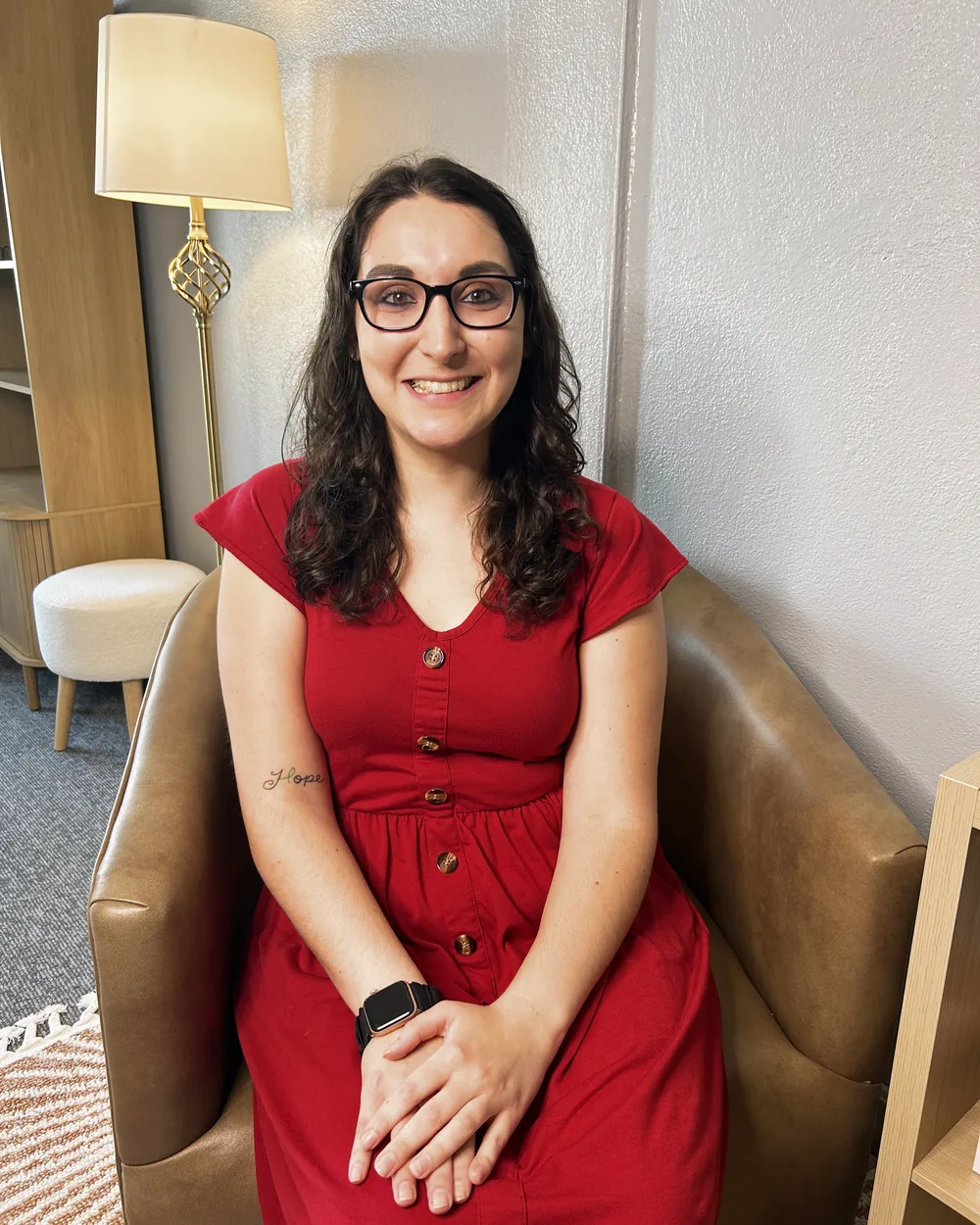 Elizabeth King in a red dress, seated in a leather chair in the New Bridges office