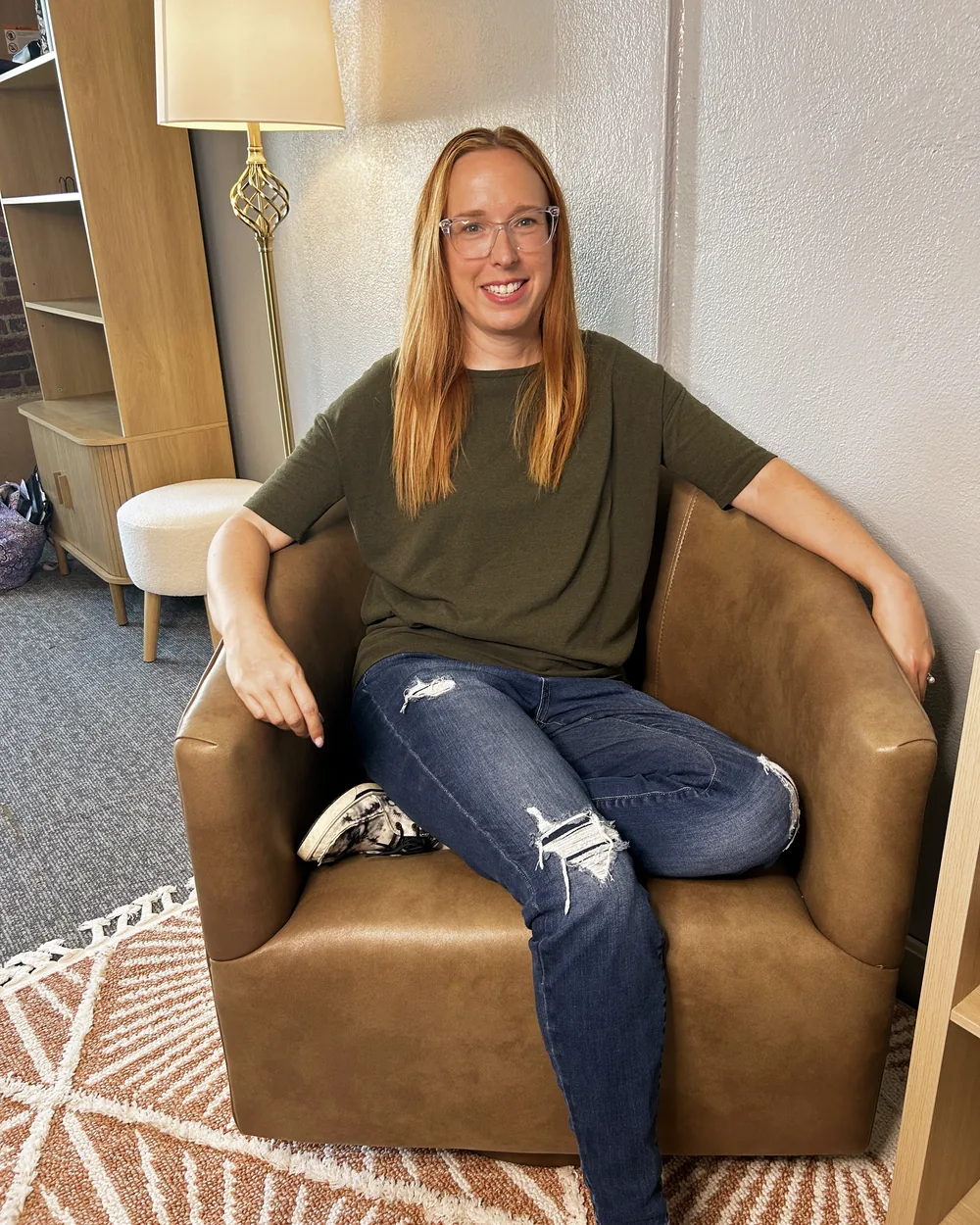Lindsey Nolan in a cognac leather chair in the New Bridges office, smiling, on the blush sunburst rug